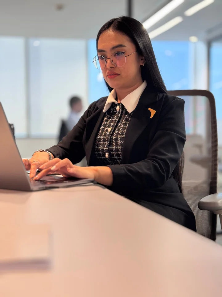 Woman working at a laptop with a drink nearby