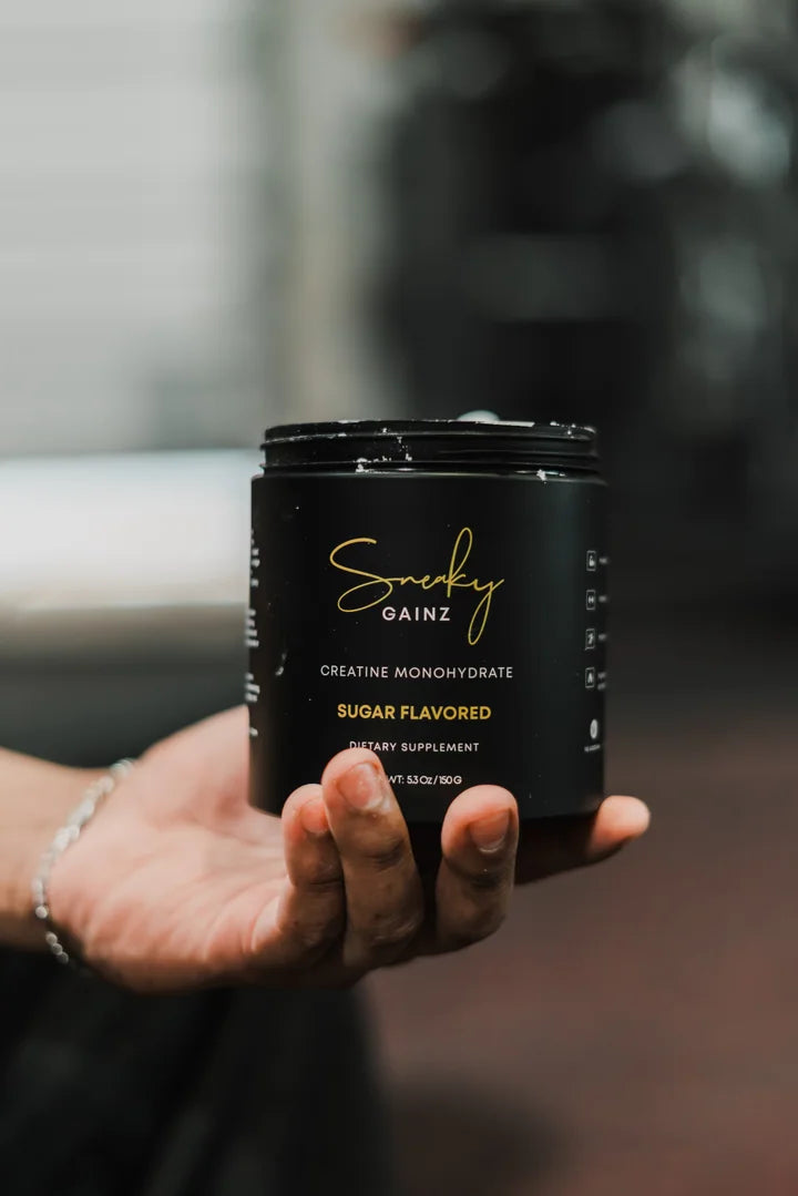 Hand holding a Sneaky Gainz creatine tub